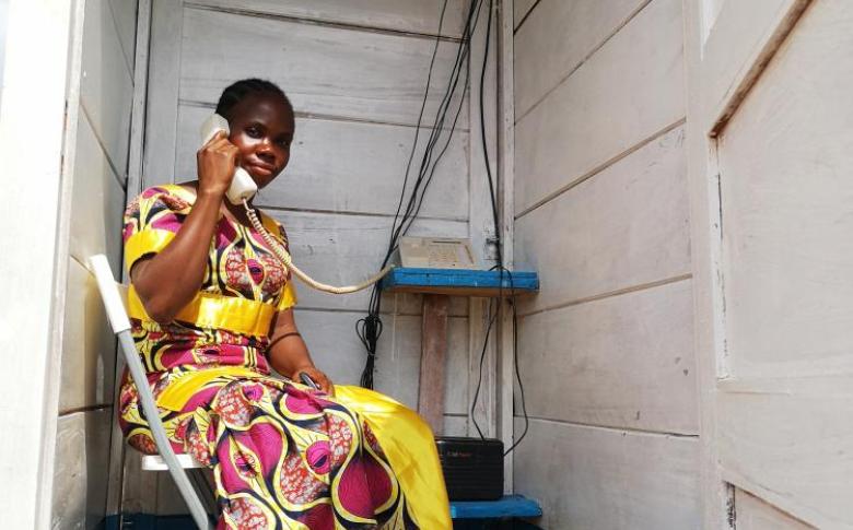 A displaced woman uses one of the new phone booths at the PK3 IDP site in Bria to stay in contact with her family. ©WFP/Elizabeth Millership, Bria, Haute-Kotto Prefecture, CAR, 2021.