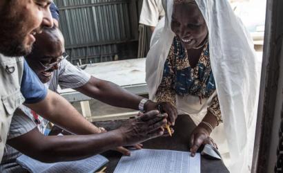 Food distribution in Al Falah Camp in Tripoli: a member of the affected population signs for her food parcels. WFP / Taha Jawashi